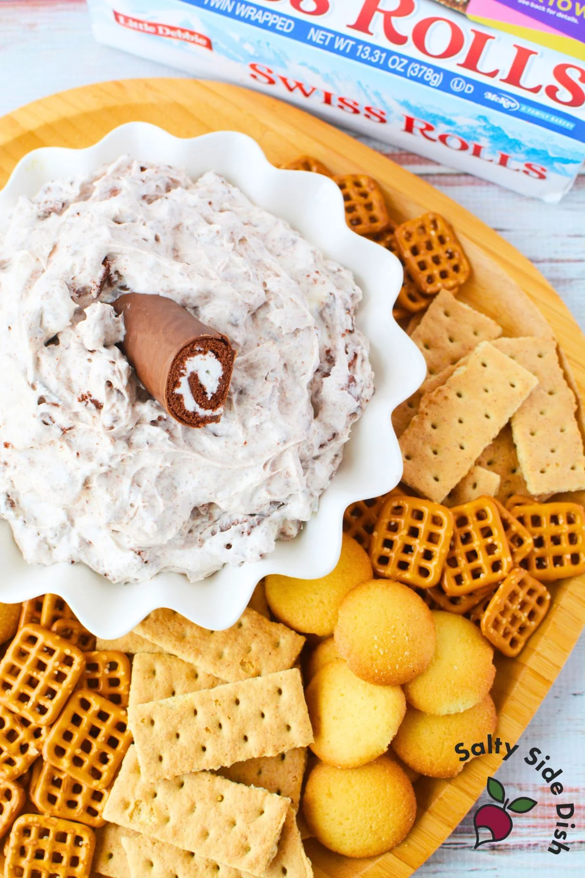 dip in a bowl with a Swiss cake on top surrounded by pretzels and cookies to dip.