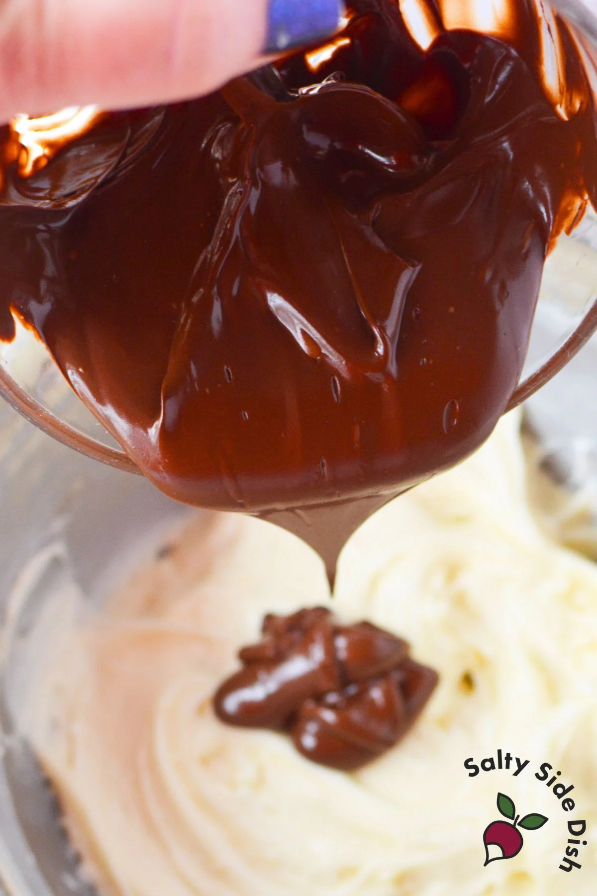 melted chocolate chips being poured into mixing bowl with cream cheese and powdered sugar.