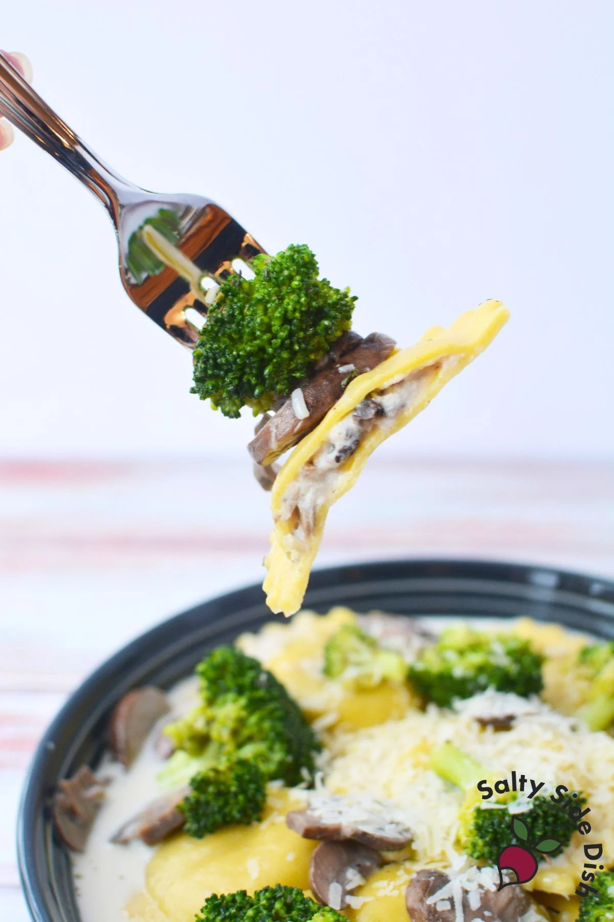 fork with broccoli, ravioli, and fresh mushrooms.