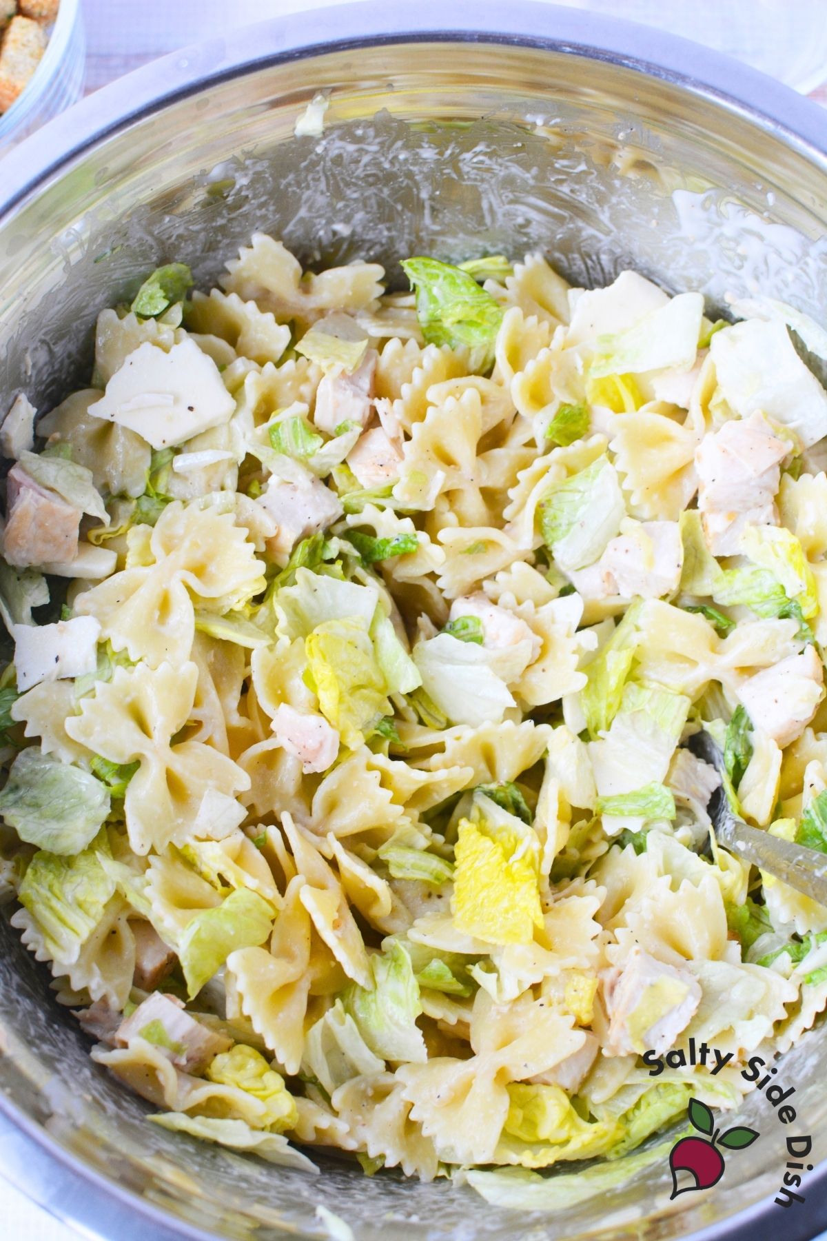 caesar pasta salad in a mixing bowl ready to add croutons.