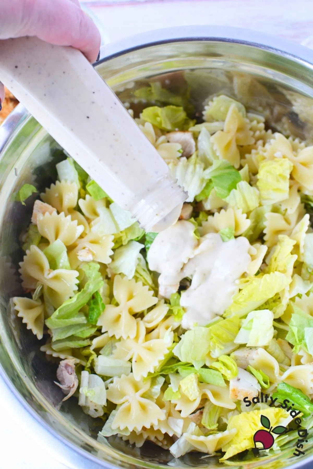 pouring Caesar salad into bowl
