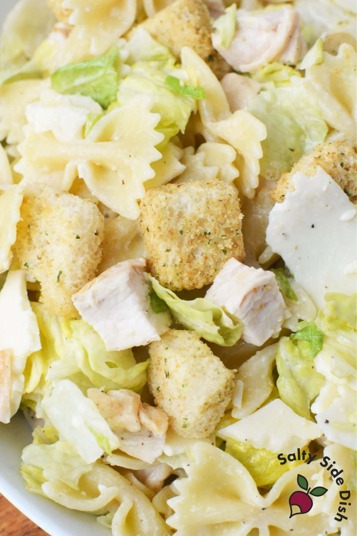chicken caesar pasta salad with croutons and shaved parmesan cheese.