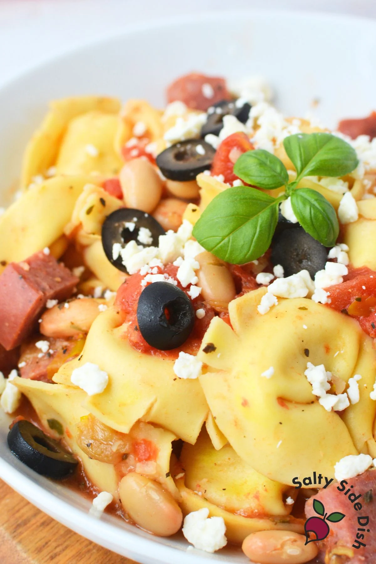 close of of tortellini dish with olives, tomatoes, and cheese.