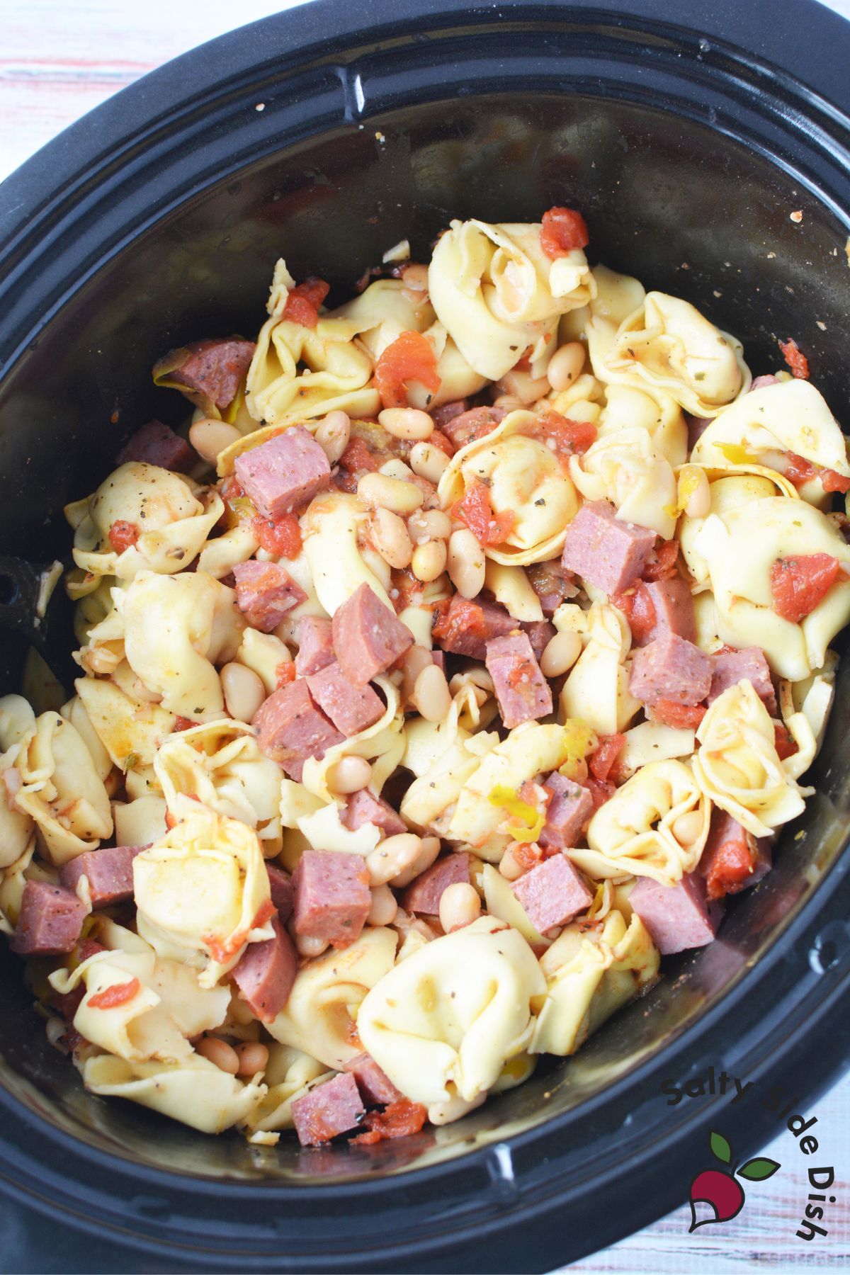 frozen tortellini, salami, and tomatoes in a slow cooker.