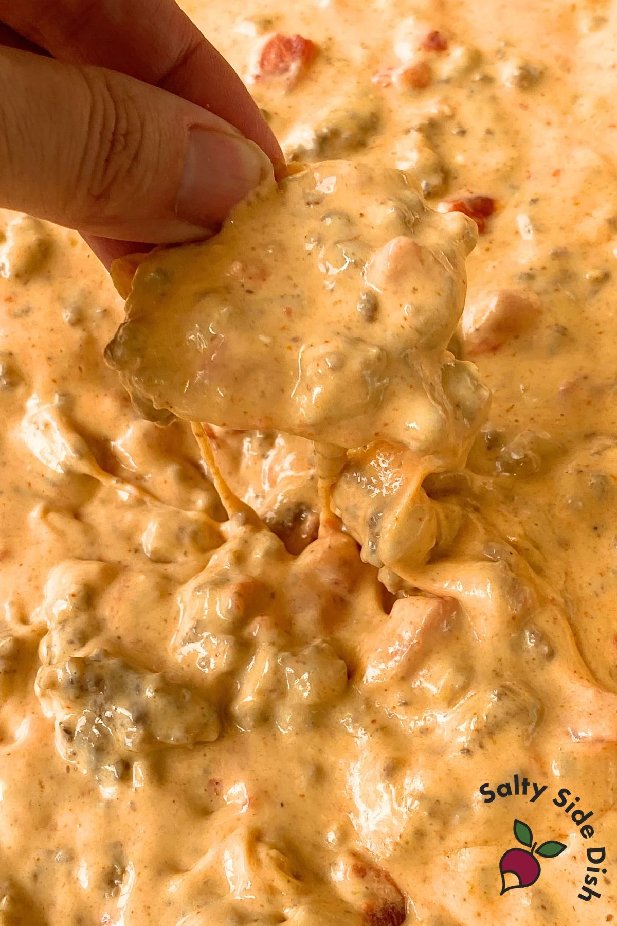 dipping tortilla chip in a cheese dip.