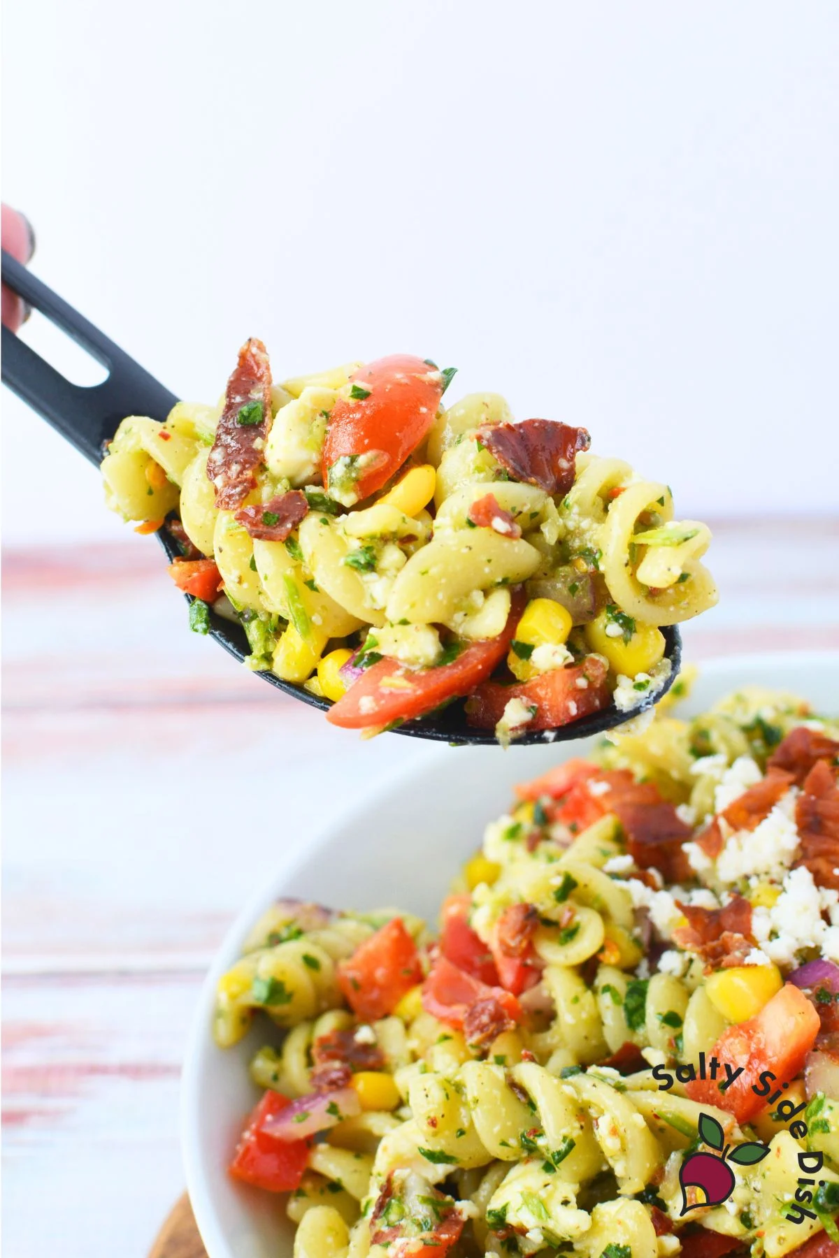 close up of black spoon with chimichurri pasta salad on it.