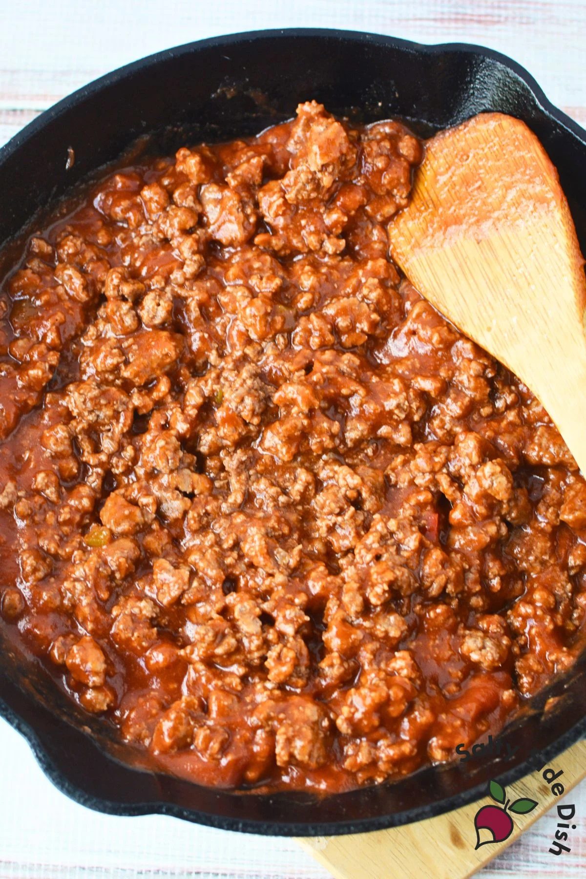 making sloppy joe with meat and a sauce in a cast iron pan.