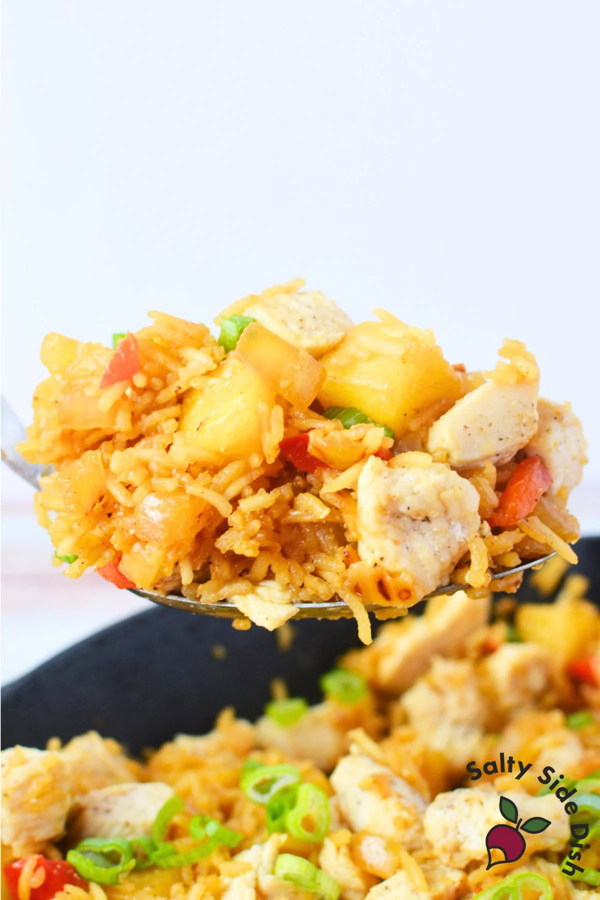 scoop of fried rice with chicken, rice, and pineapple and green onions.