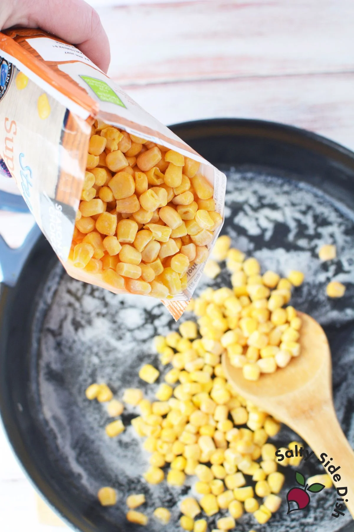 adding frozen corn to a cast iron skillet.