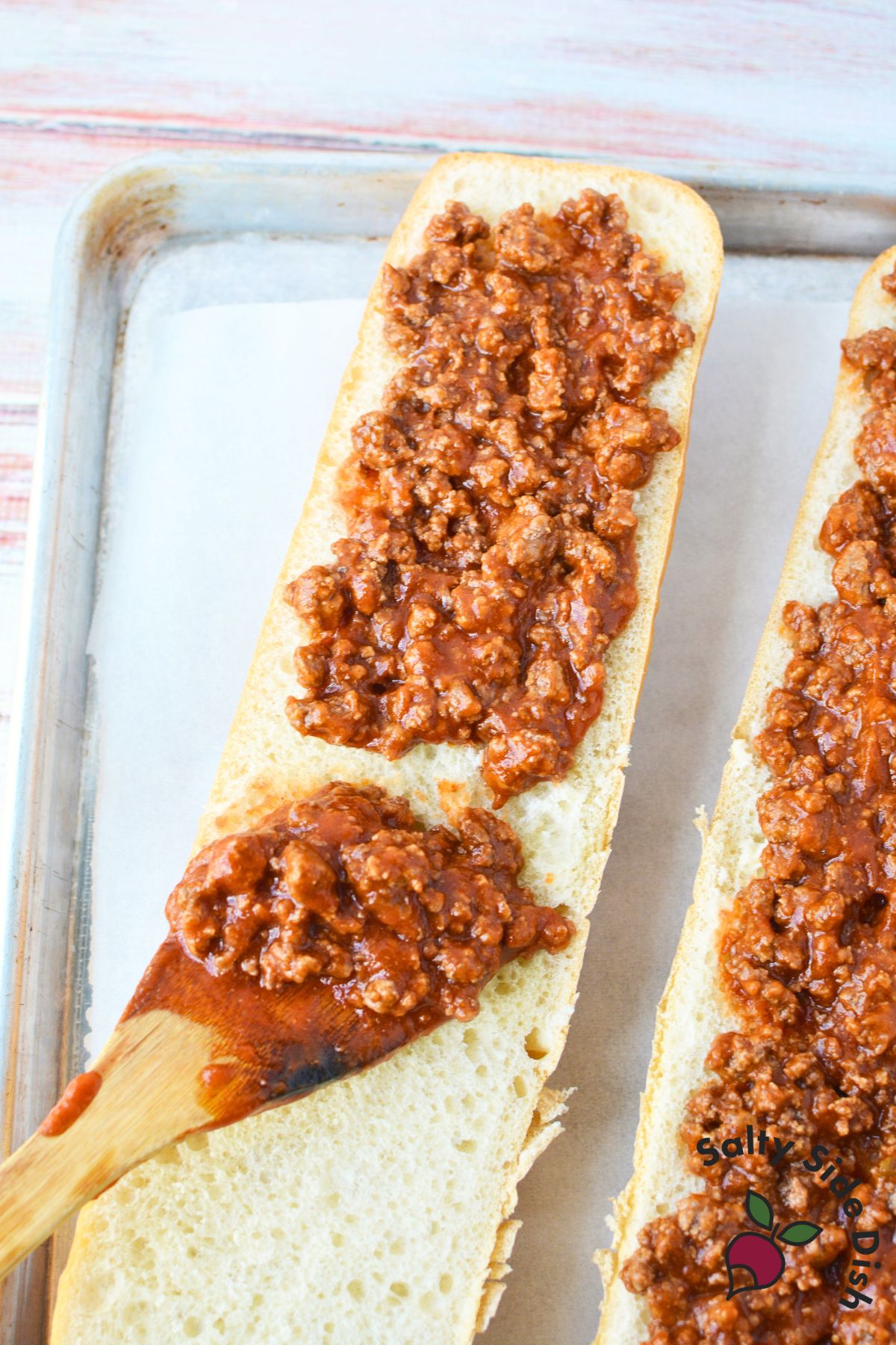 adding meat onto french bread pieces.