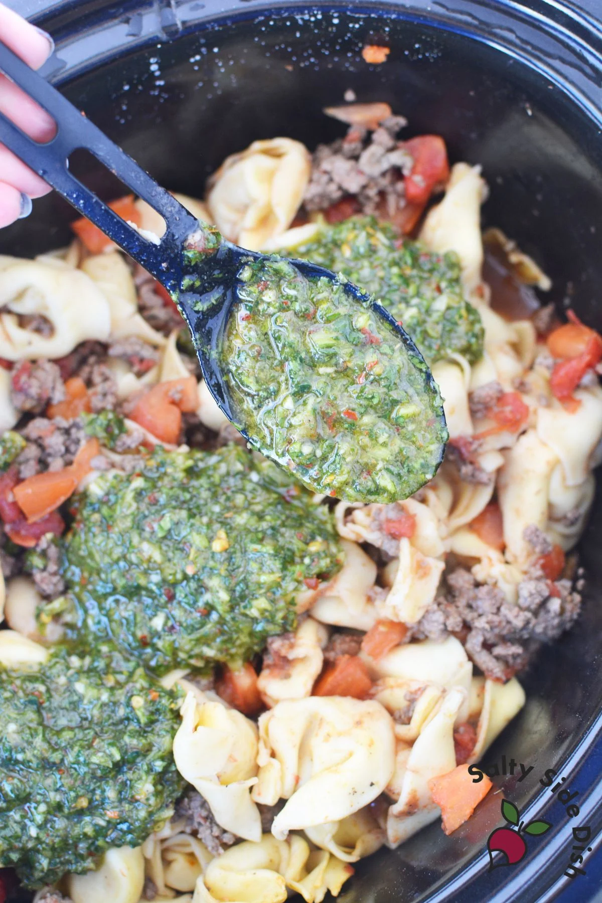 chimichurri being spread on sausage tortellini dinner.