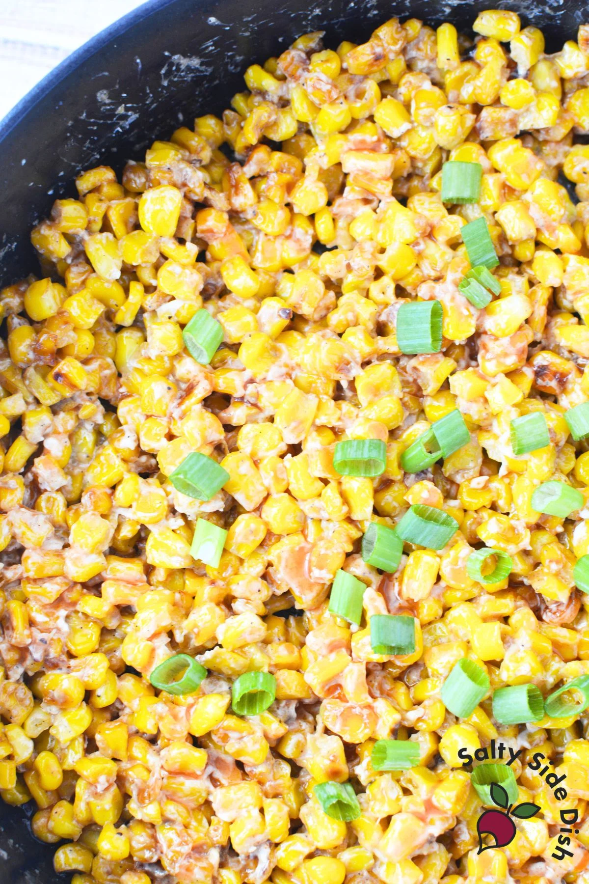stovetop corn side dish with honey, cream cheese, butter, and browned up in a cast iron pan.