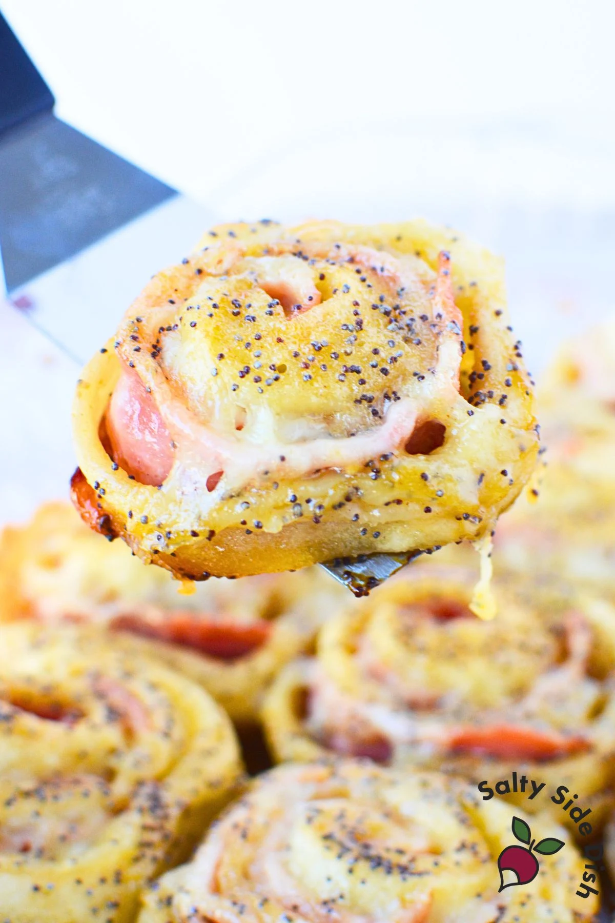 Freshly baked ham and cheese pinwheels in a glass baking dish, golden and bubbly with buttery glaze