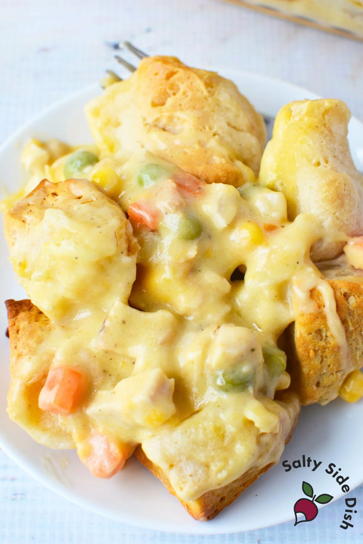 Close-up of chicken pot pie with vegetables and flaky biscuit pieces.