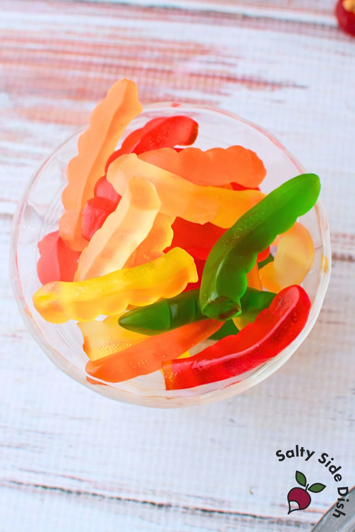 Colorful gummy worms in a clear glass bowl for topping Oreo dirt cups.