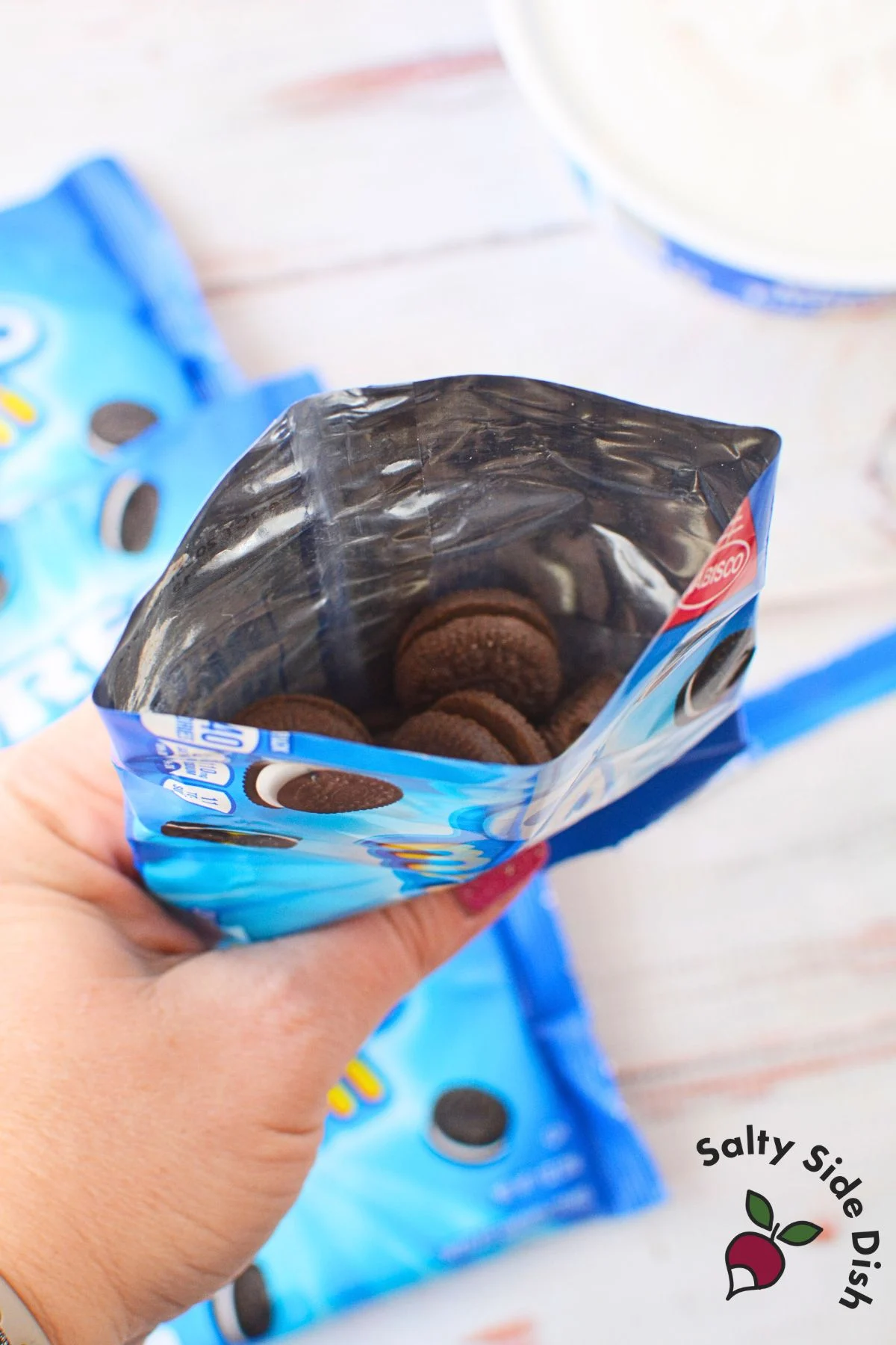 A hand holding a mini Oreo bag with the top cut to prep for dirt dessert.