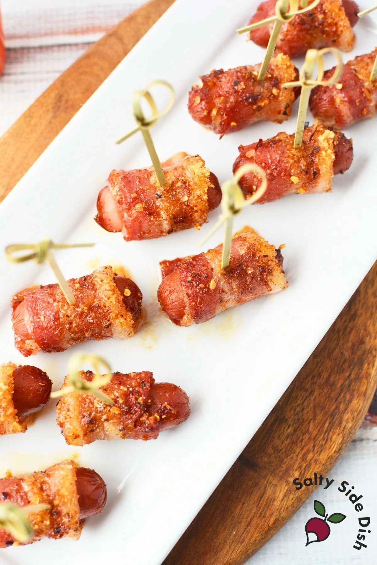 Bacon-wrapped Li’l Smokies arranged on a white platter with toothpicks for serving.