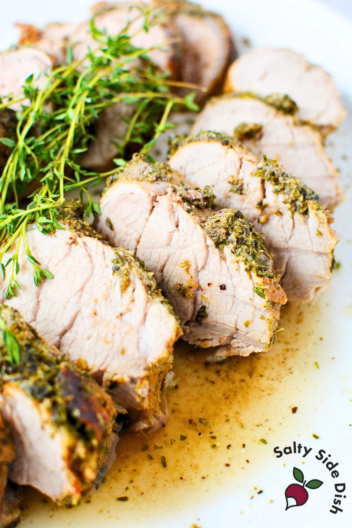 Juicy sliced pork tenderloin topped with fresh thyme and surrounded by pan juices
