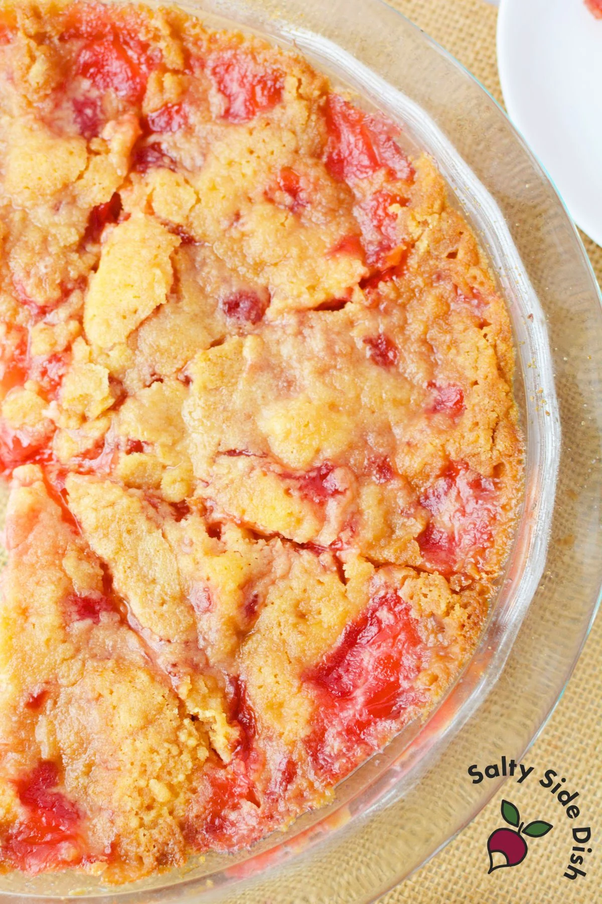 Overhead shot of freshly baked cherry impossible pie with golden topping and cherry filling in a glass pie plate
