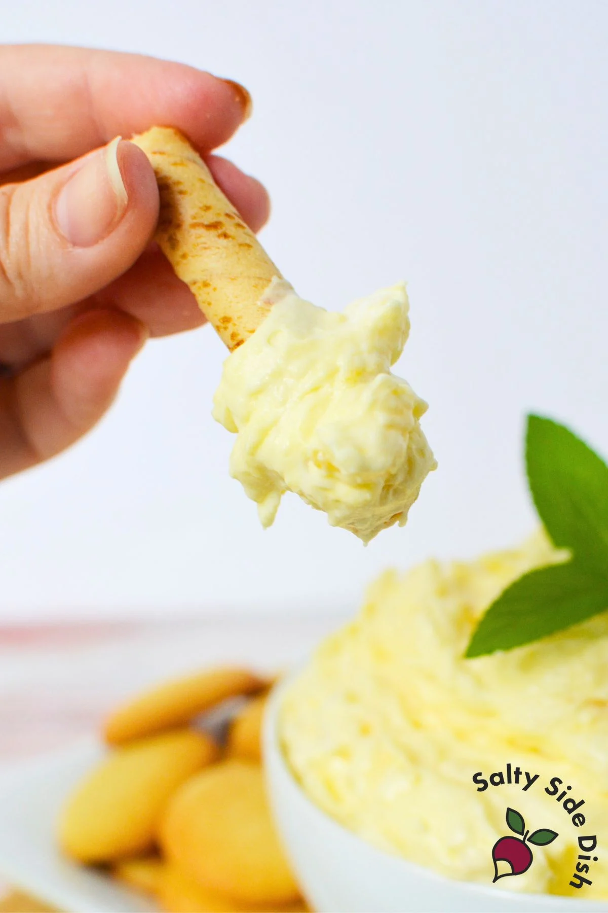 Spoonable pineapple pudding dip served on a vanilla wafer stick, perfect for parties or snacks