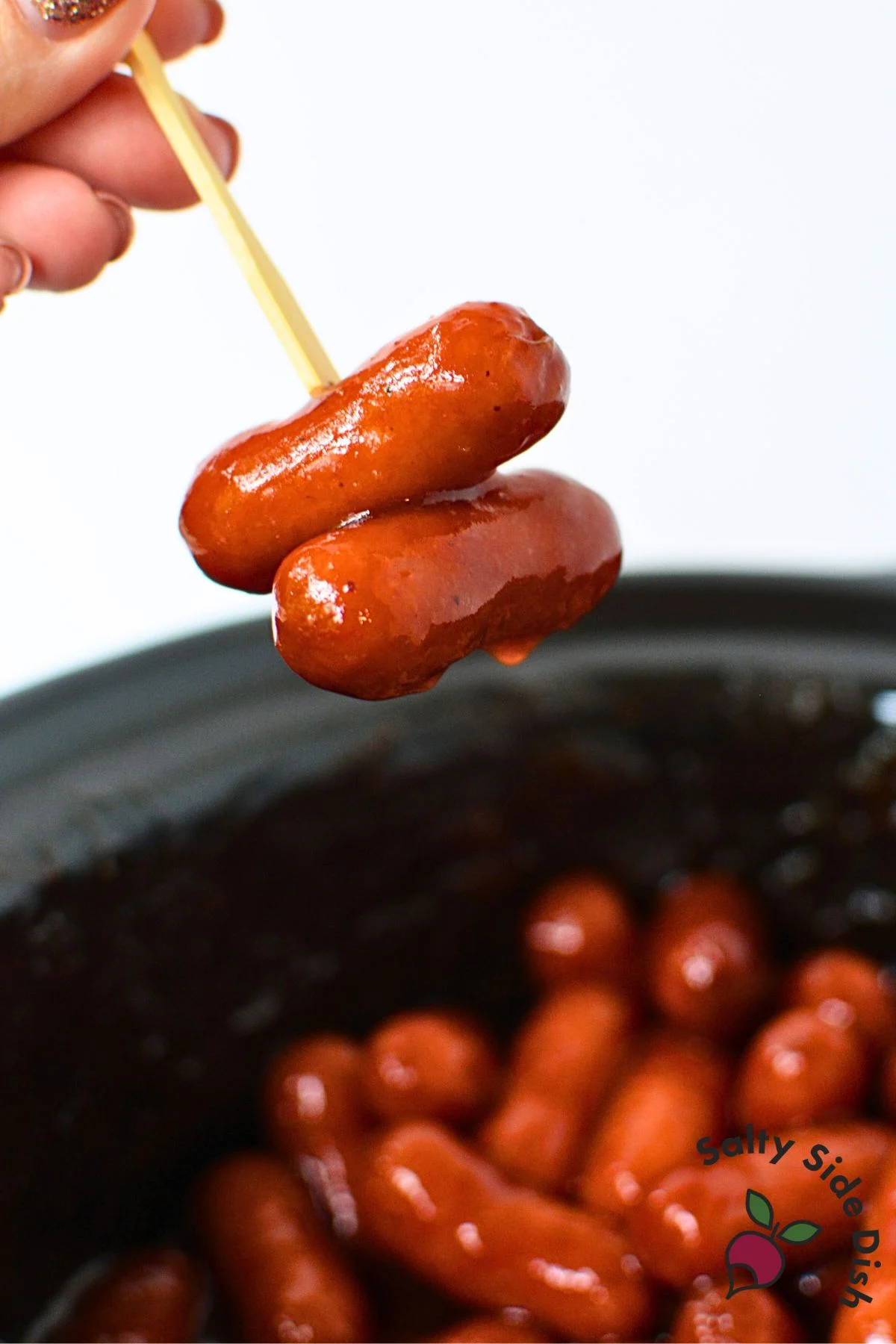 Two little smokies on a bamboo toothpick over a crockpot