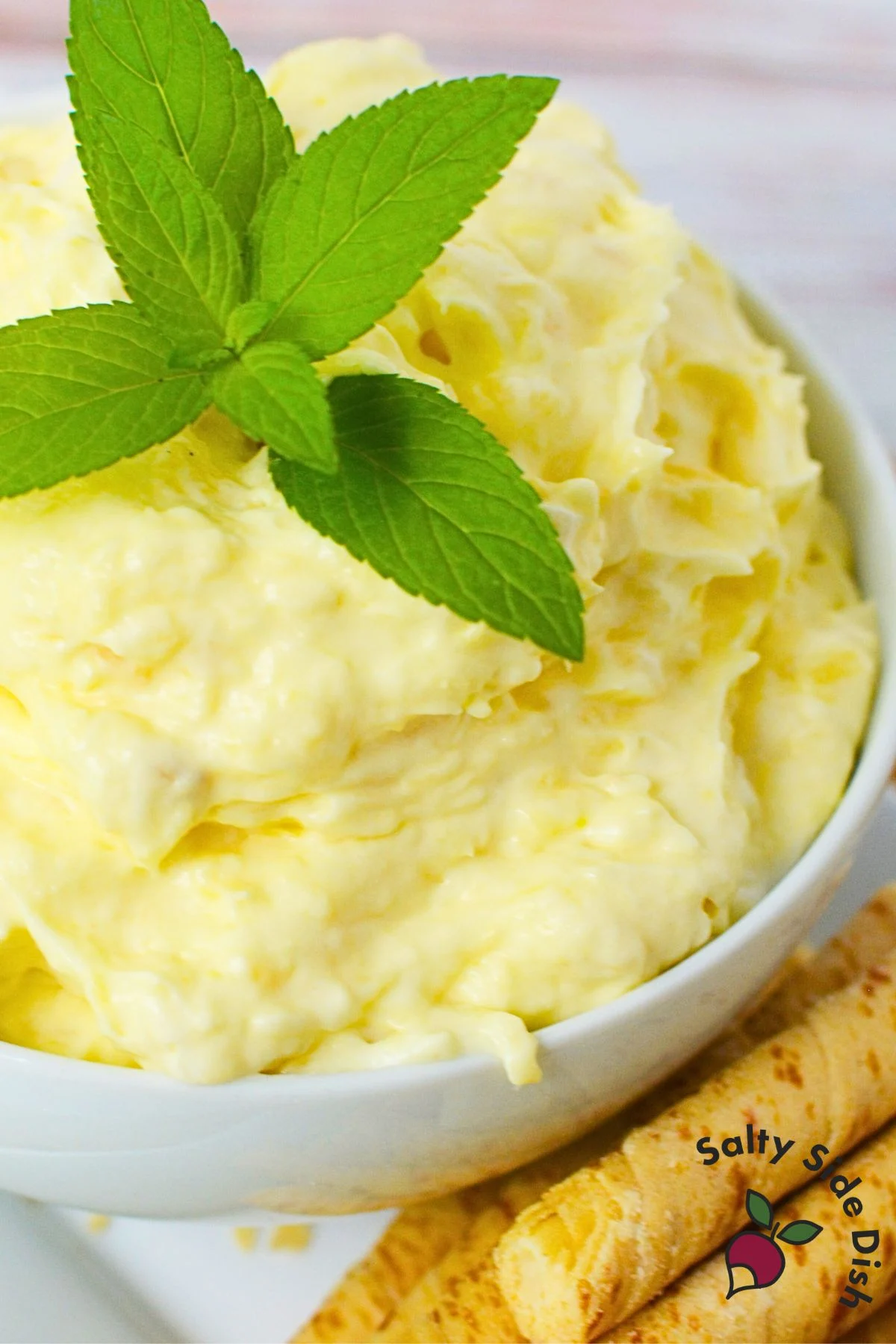 Close-up of finished pineapple dip recipe in bowl with fresh mint and vanilla sticks for dipping