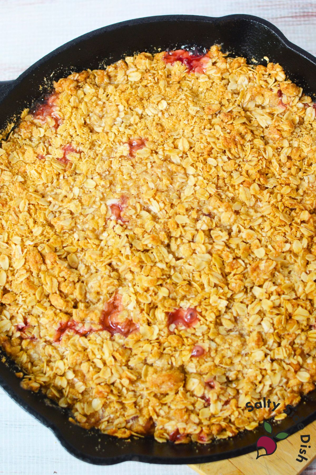 Freshly baked rhubarb crisp with golden brown oat topping in a cast iron skillet.