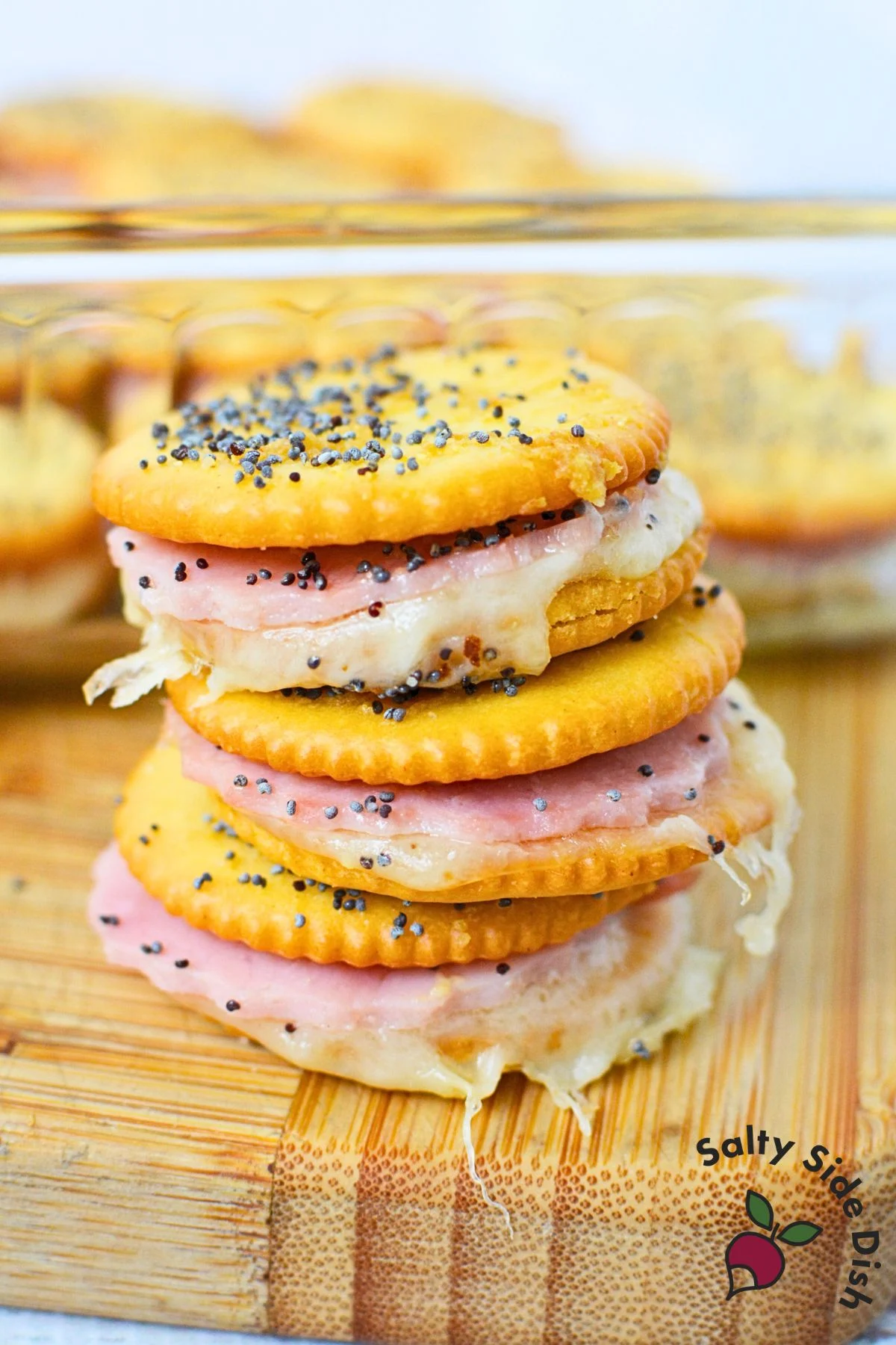 Stacked Ritz cracker party sandwiches in a baking dish with cheesy ham filling.