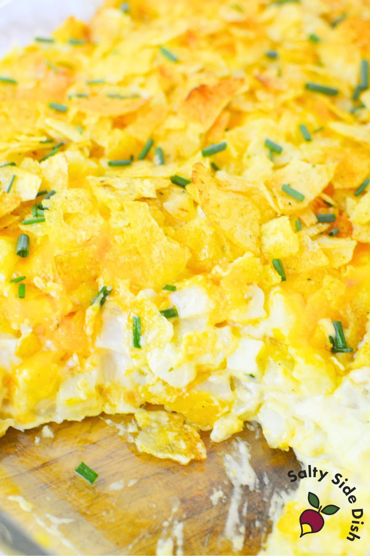 Inside of the baked sour cream and onion casserole showing melted cheese, creamy texture, and crushed chips on top.