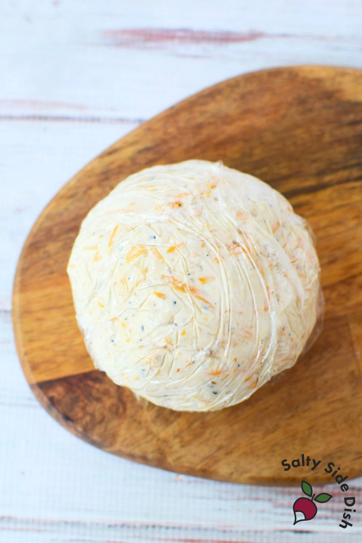 Cheese ball wrapped in plastic wrap before chilling to set