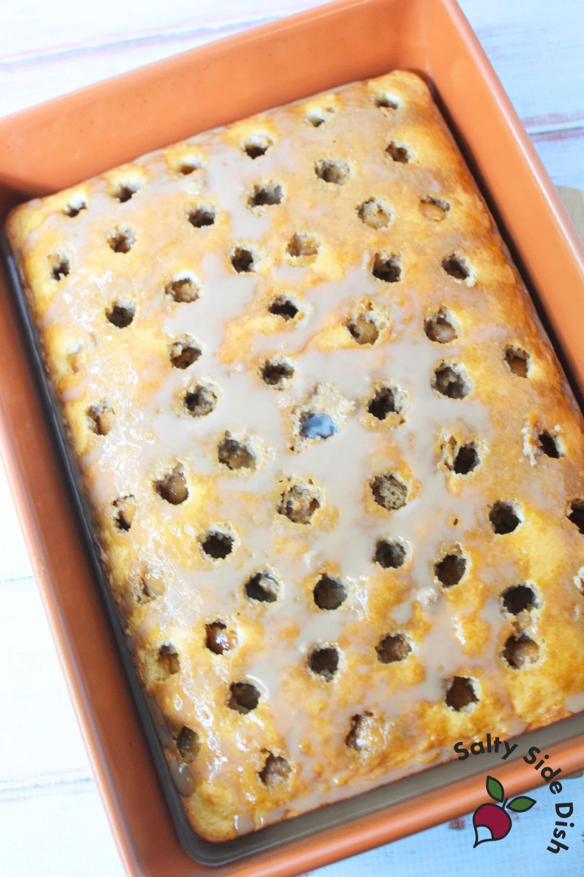 Freshly baked white cake with poke holes filled with coffee and condensed milk for tiramisu poke cake recipe.