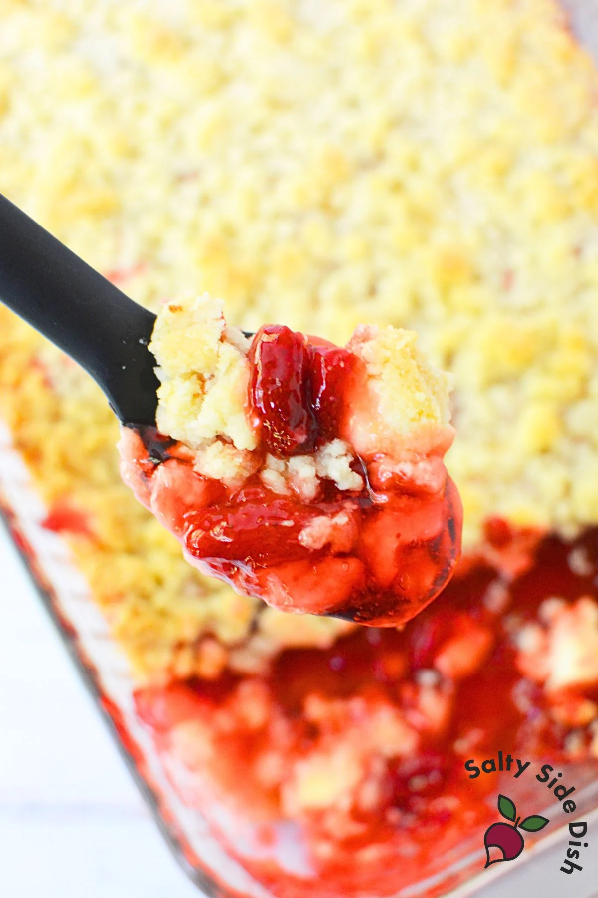 Overhead view of strawberry dump cake served with ice cream alongside baking dish.