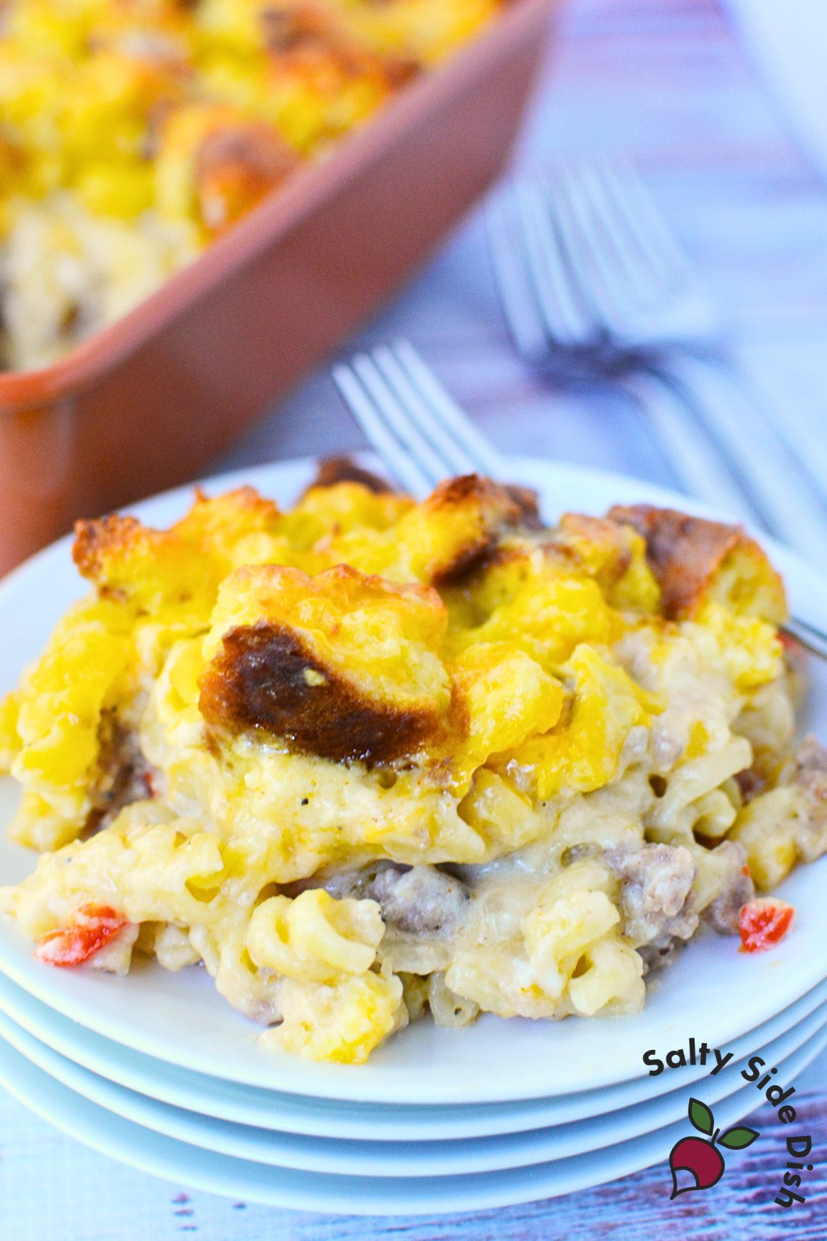 serving of breakfast sausage pasta bake with pasta, sausage, cheese, and biscuit topping on a plate