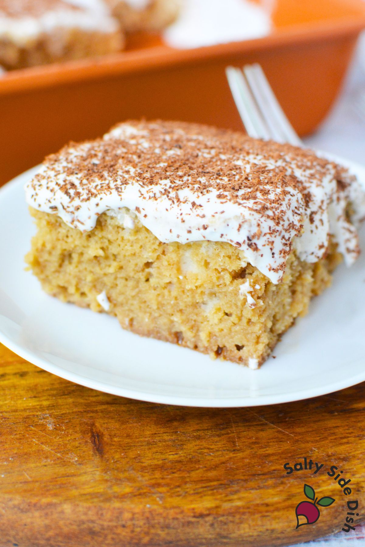 Easy tiramisu poke cake with mascarpone topping and chocolate shavings served from a 9x13 pan.