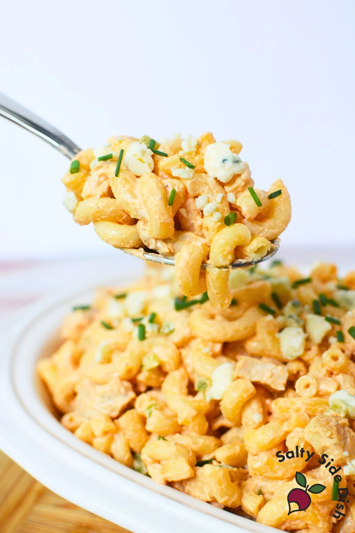 Spoonful of buffalo chicken pasta salad with chicken, pasta, blue cheese, and chives