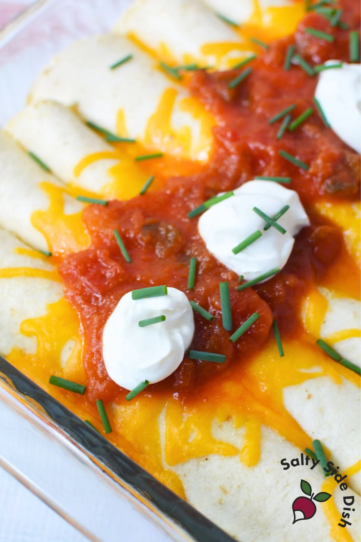 Cheesy breakfast enchilada filled with ham and eggs, topped with salsa and sour cream for a filling morning meal.