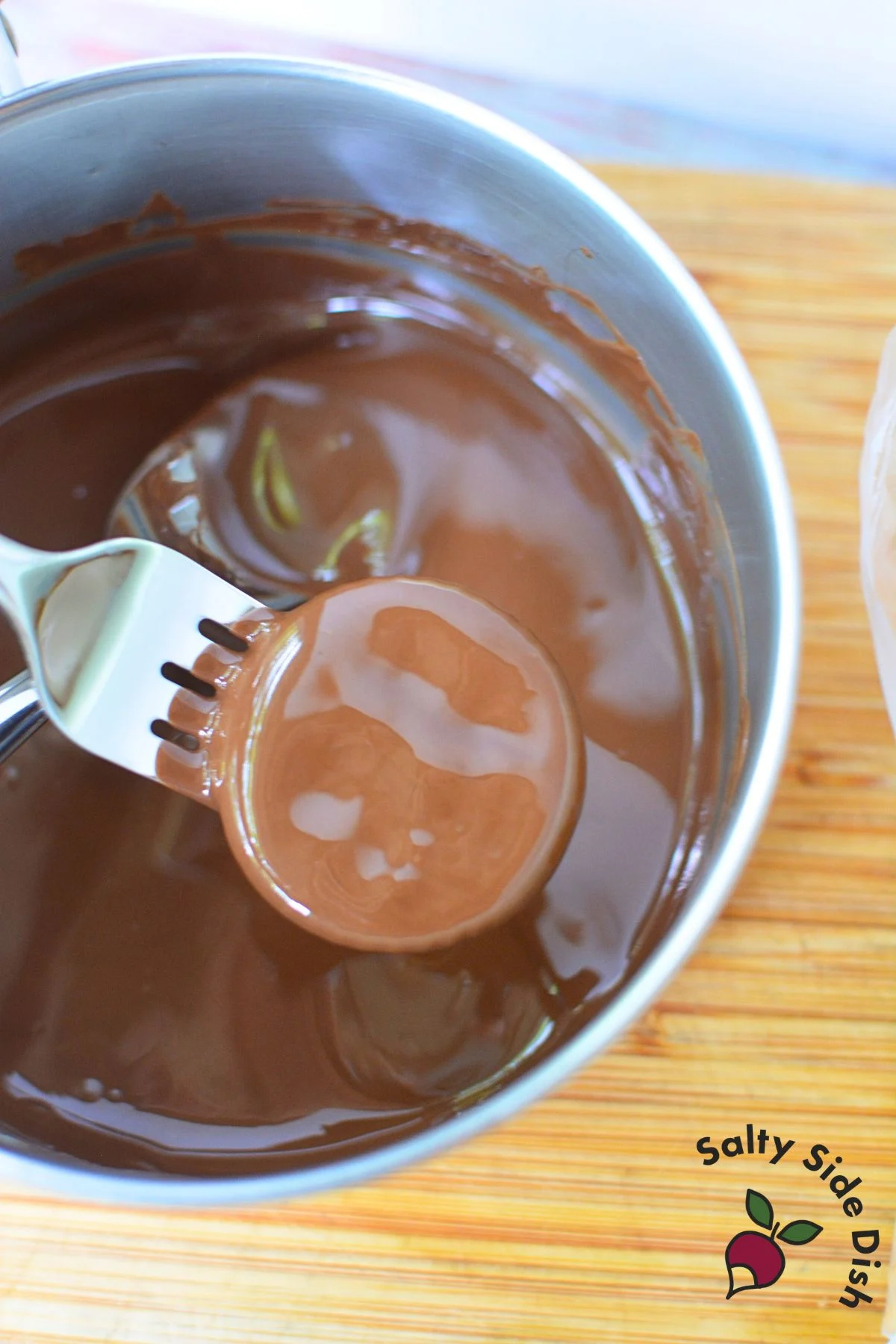 Ritz cracker being dipped into melted Andes chocolate with fork