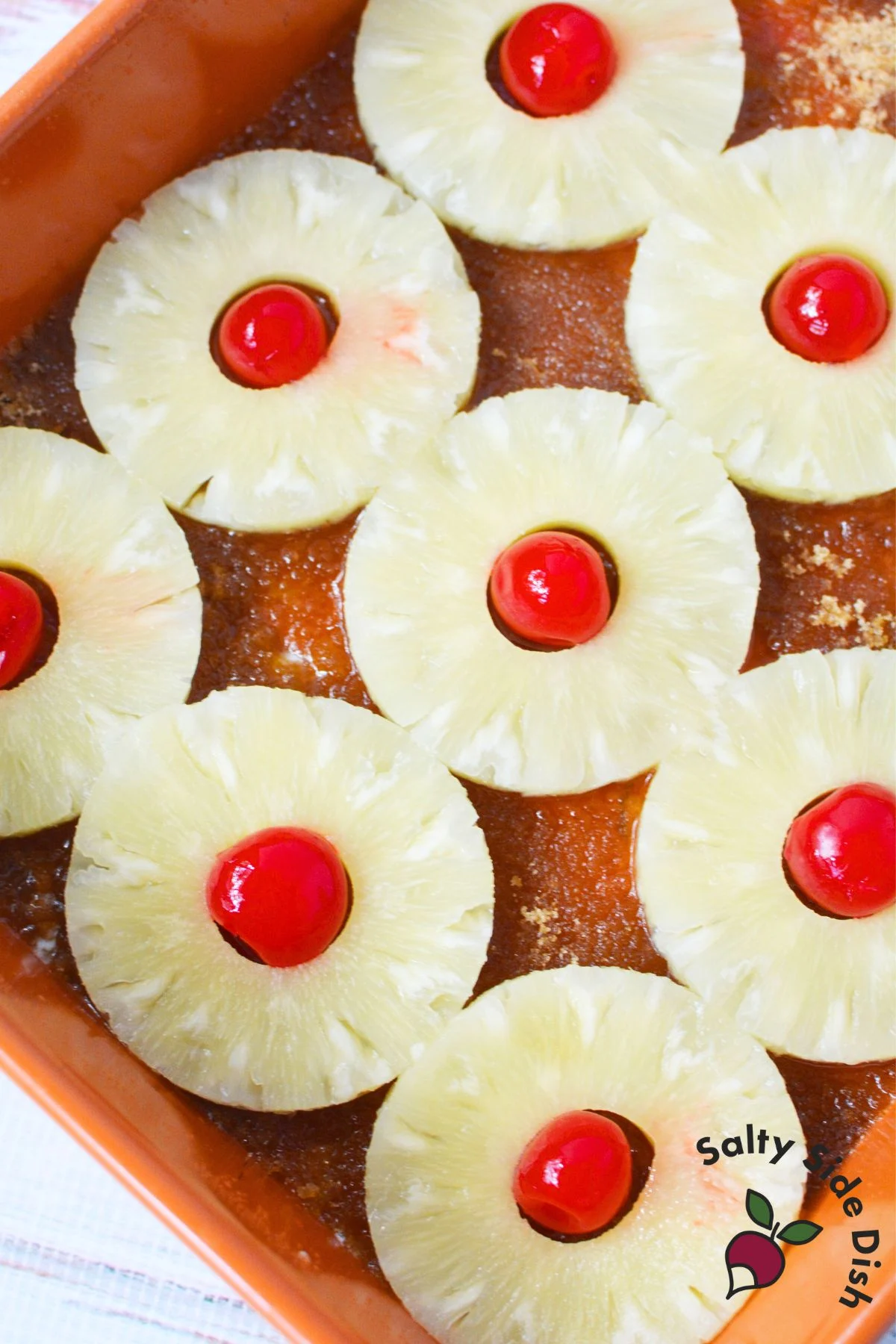 Pineapple slices with maraschino cherries placed in the center on top of brown sugar layer before baking.