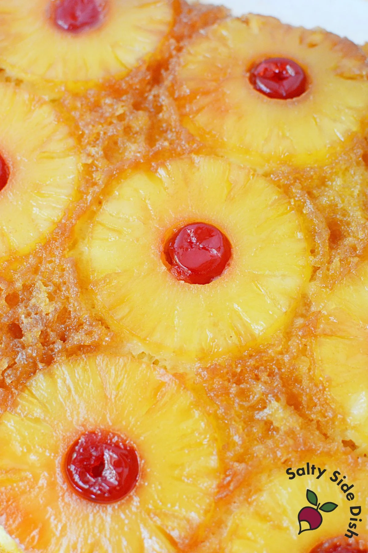 Freshly baked pineapple upside down cake flipped out of the pan with caramelized pineapple rings and cherries.