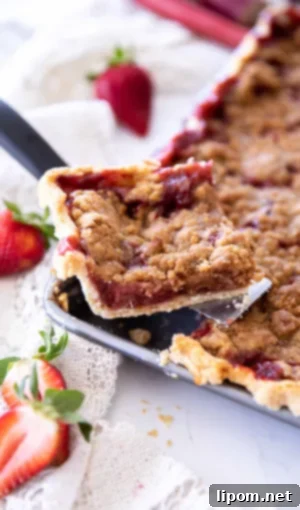 Luscious Caramel Apple Crumble Bars 4 Strawberry rhubarb crumb bar slice sitting on a pie server, reminiscent of a classic strawberry rhubarb slab pie with a brown sugar crumb topping.