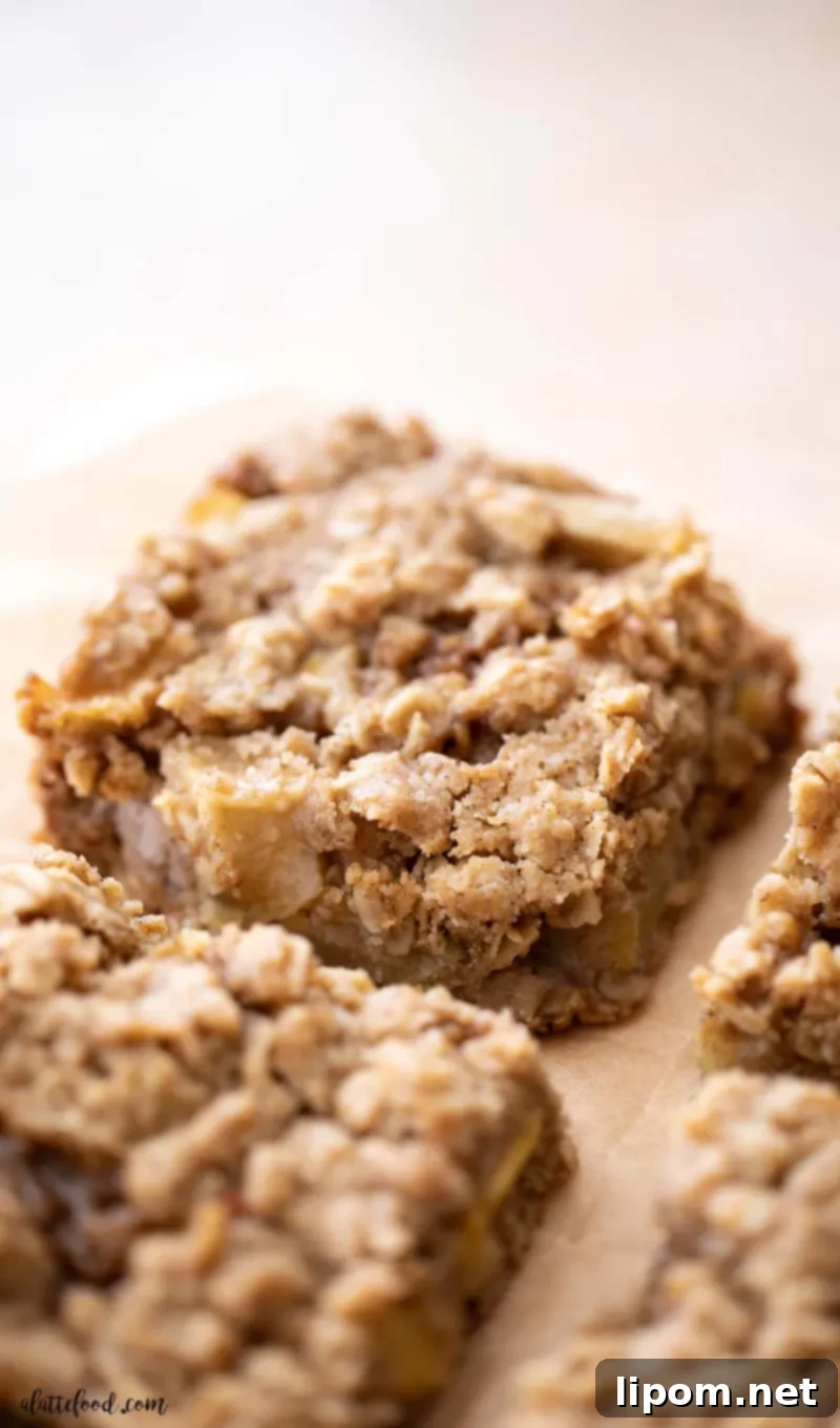 Sliced Caramel Apple Crumb Bars with Oatmeal Streusel Baked apple pie crumb bars sliced on brown parchment paper, showcasing the irresistible combination of apple pie, apple crisp, and oatmeal cookies in one delicious treat.