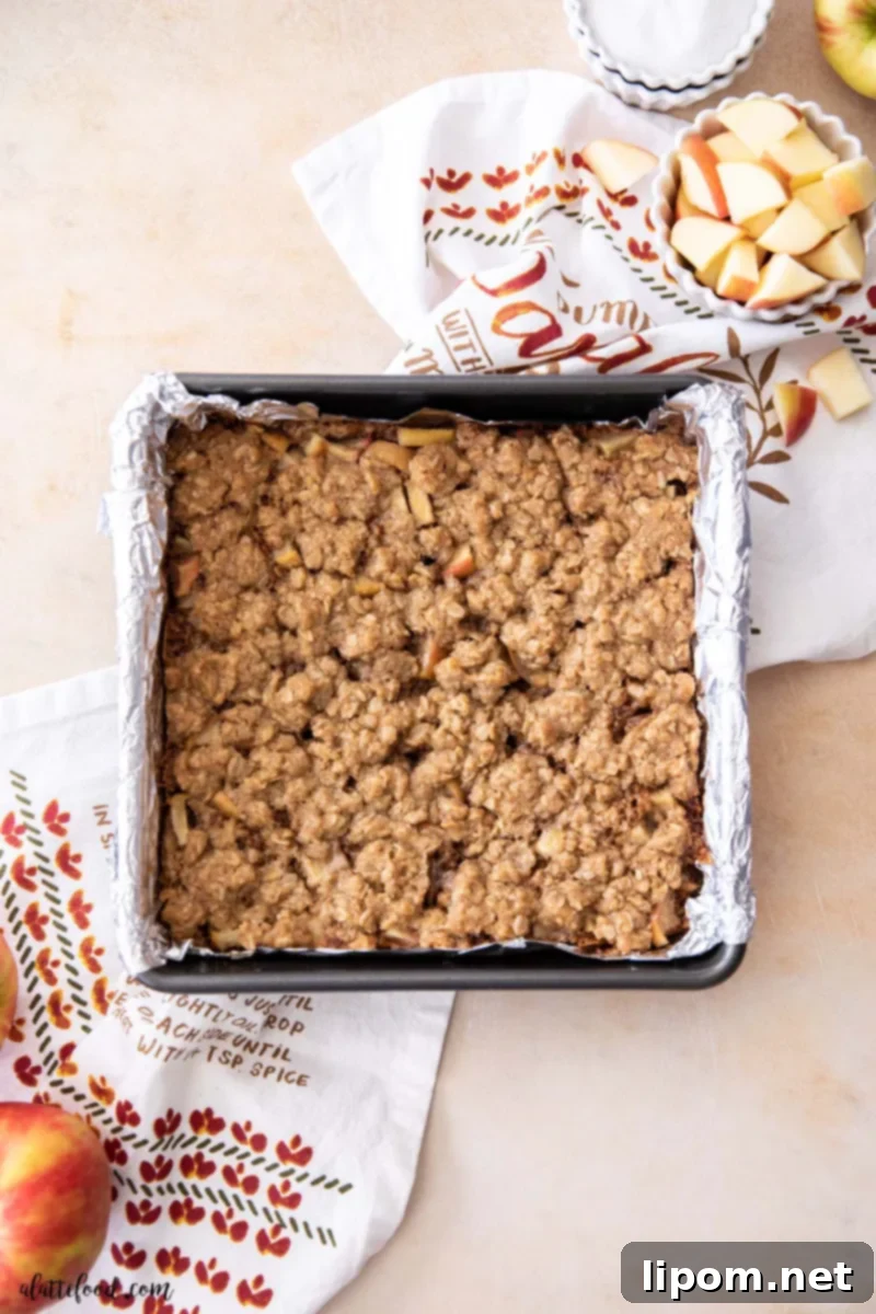 Freshly Baked Caramel Apple Crumb Bars Baked caramel apple crumb bars in a foil-lined baking dish, showcasing the brown sugar oat crust and a rich caramel apple pie filling.