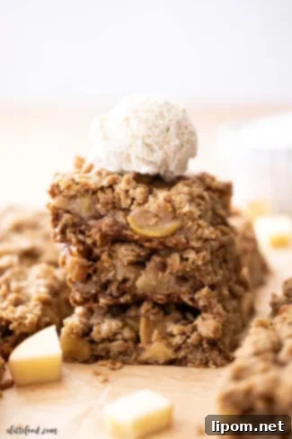 Luscious Caramel Apple Crumble Bars 2 ice cream topped apple crumb bars on parchment paper.