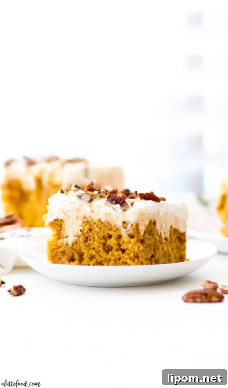 Pumpkin Poke Cake with cream cheese frosting on white plate