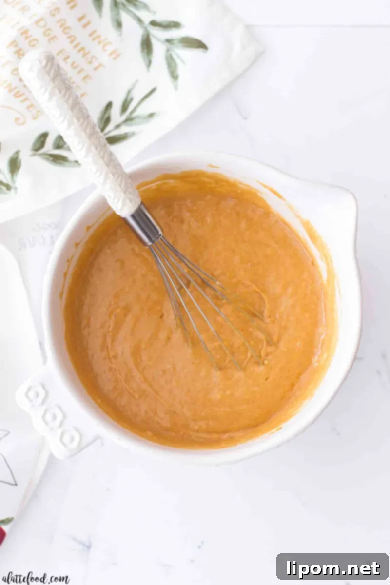 pumpkin poke cake batter in a white mixing bowl