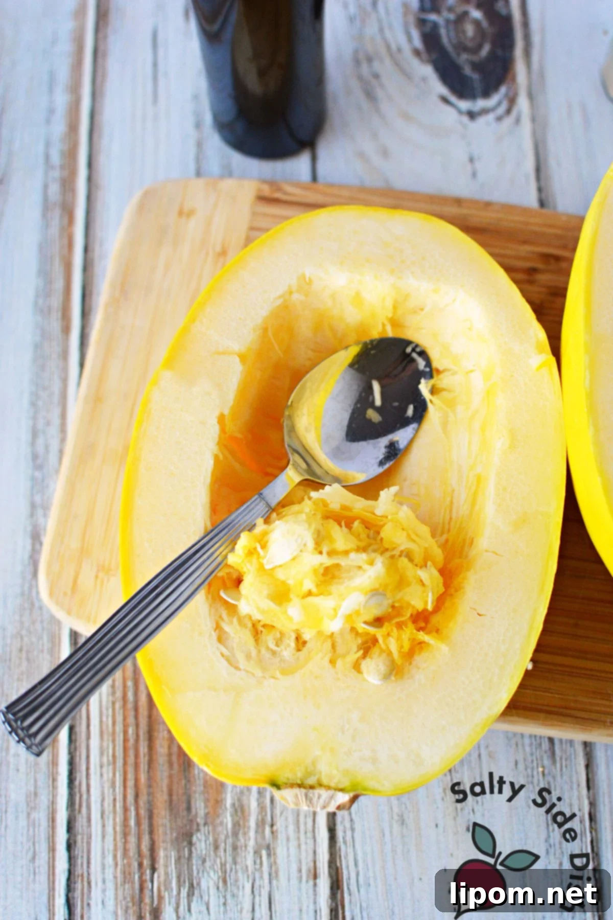 Mastering Spaghetti Squash 4 scrapping seeds out of spaghetti squash half.