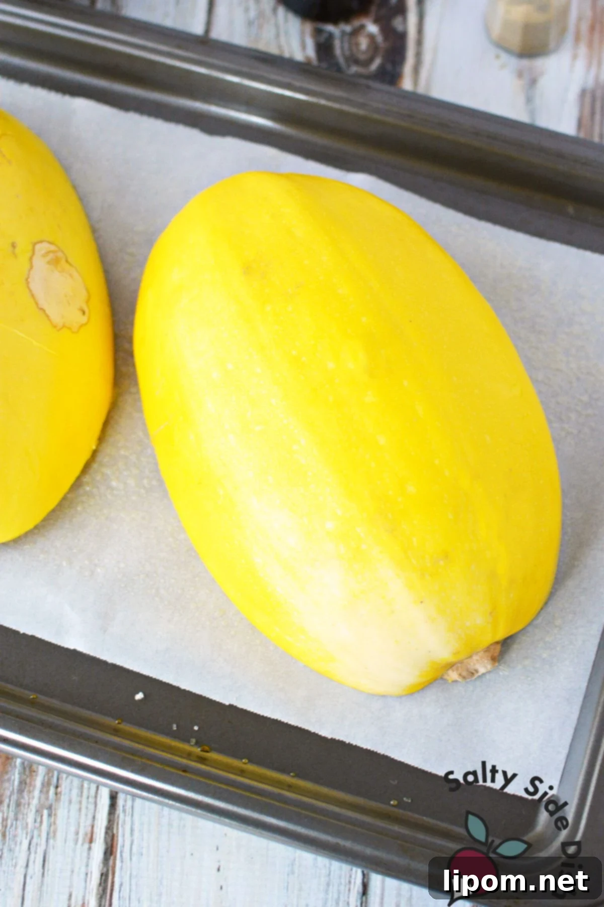 Mastering Spaghetti Squash 7 squash on parchment paper on a cookie sheet.