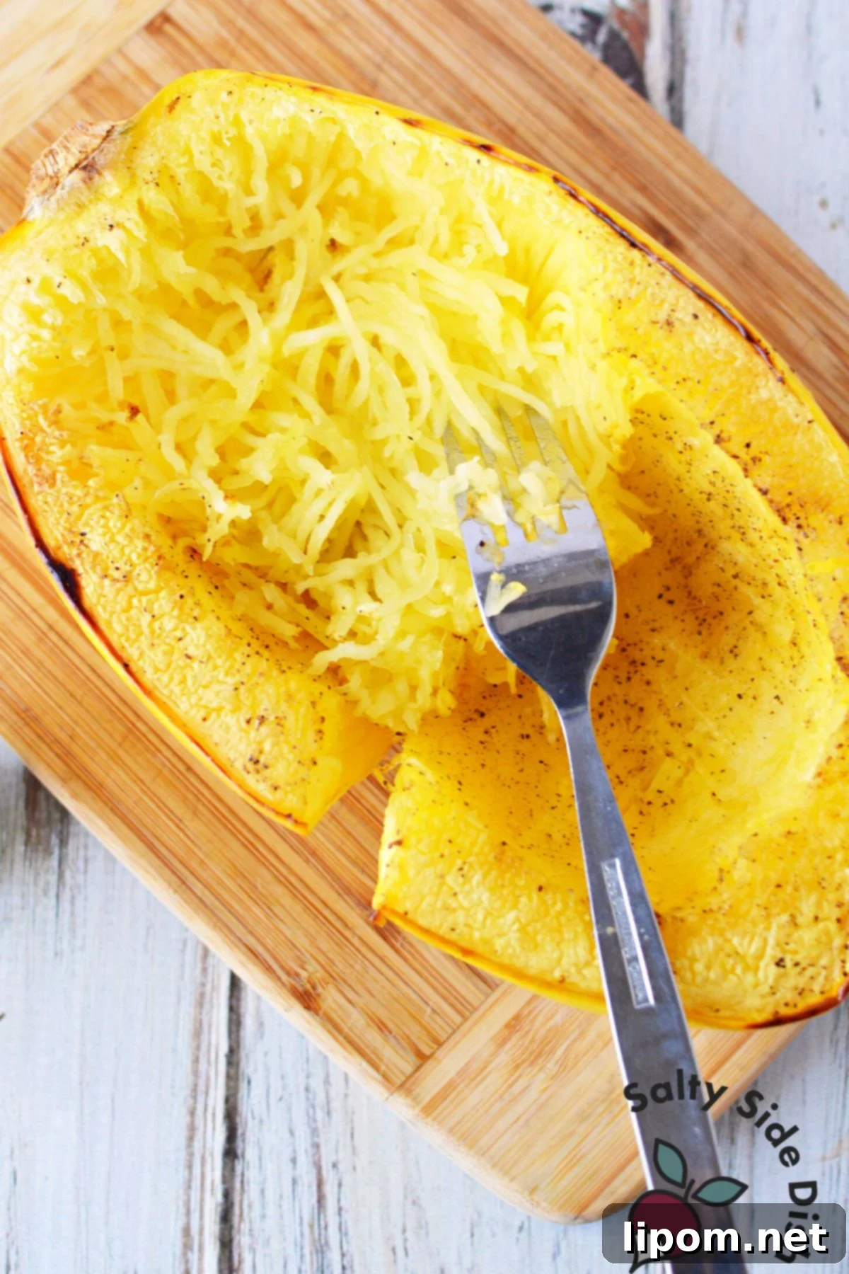 Mastering Spaghetti Squash 8 peeling squash strands from the inside of a cooked spaghetti squash.