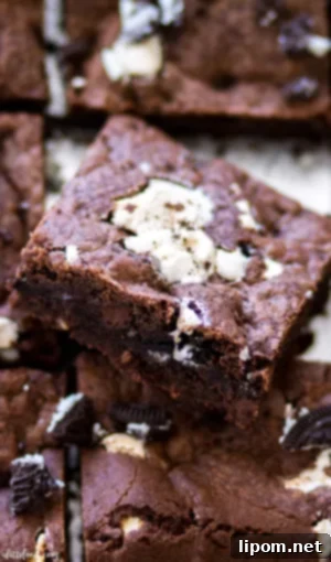 Squares of gooey double chocolate Oreo cookie bars, topped with marshmallow cream and chocolate, presented in a metal baking dish. These decadent bars are ultra gooey and perfect for chocolate and cookie lovers.