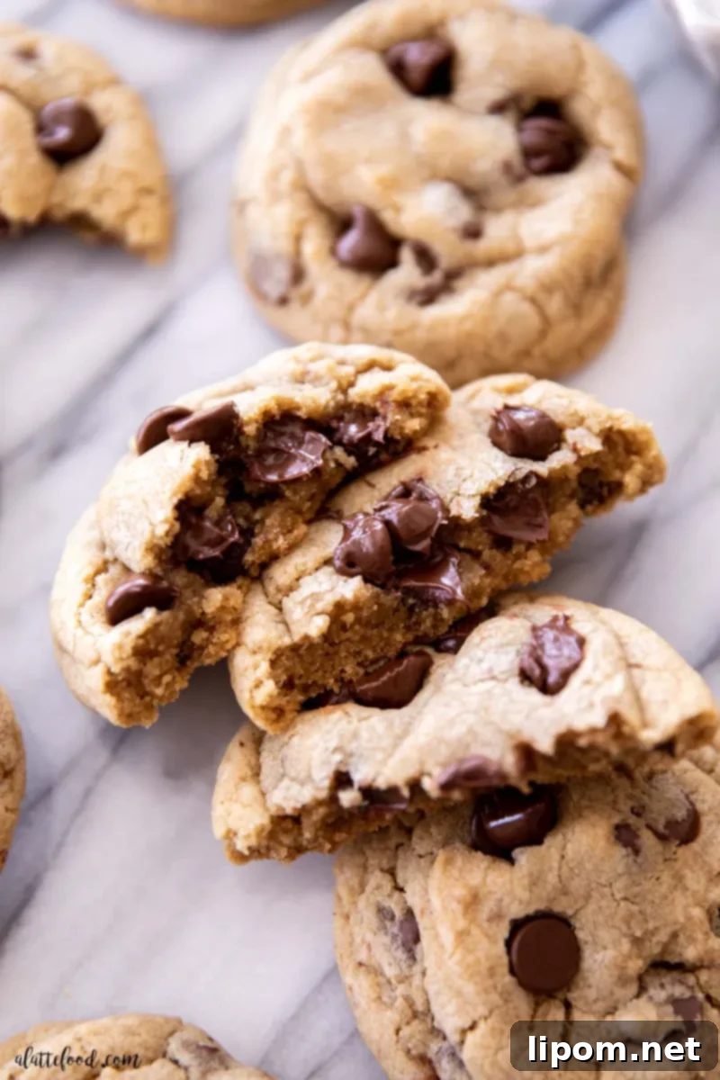 A close-up shot of homemade chocolate chip cookies, cut in half and resting on a elegant marble board, showcasing their rich, gooey chocolate and tender interior. This classic recipe is designed for perfect soft and chewy cookies every time.